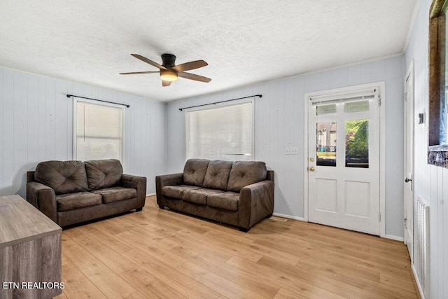 living room featuring a ceiling fan, light wood-style flooring, and a textured ceiling