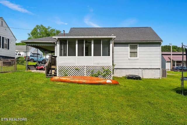 back of house with a lawn, a sunroom, fence, and a carport