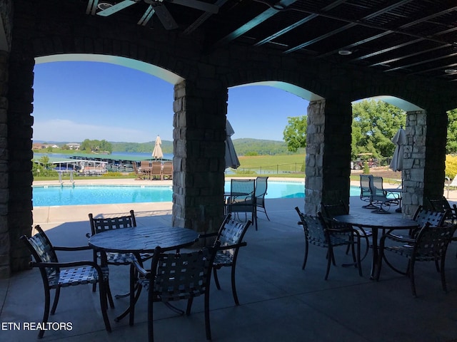 view of patio with outdoor dining area, a community pool, and ceiling fan