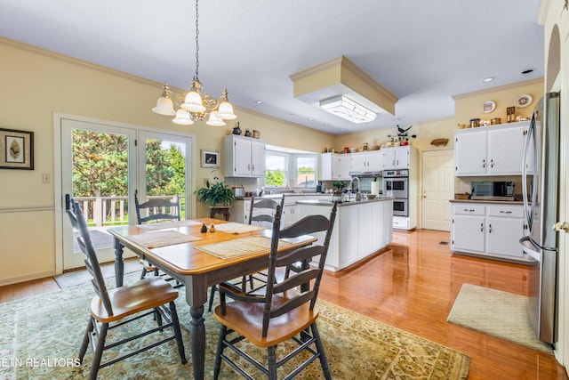 dining room with light wood finished floors, an inviting chandelier, and crown molding