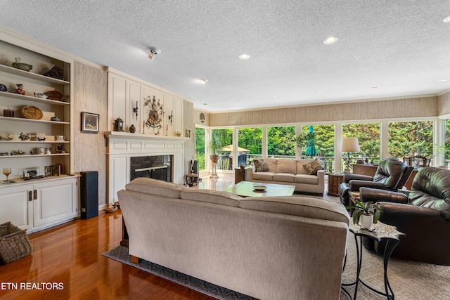 living room with a premium fireplace, a textured ceiling, recessed lighting, and wood finished floors