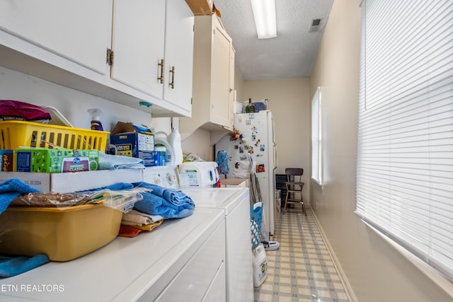 laundry area featuring cabinet space, light floors, a textured ceiling, visible vents, and washing machine and clothes dryer