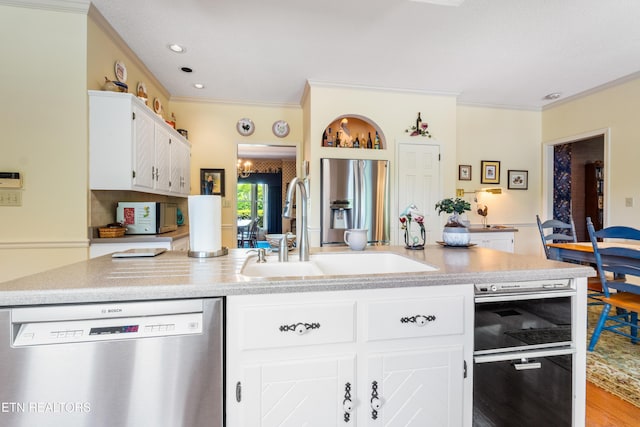 kitchen featuring a sink, stainless steel appliances, ornamental molding, white cabinetry, and light countertops