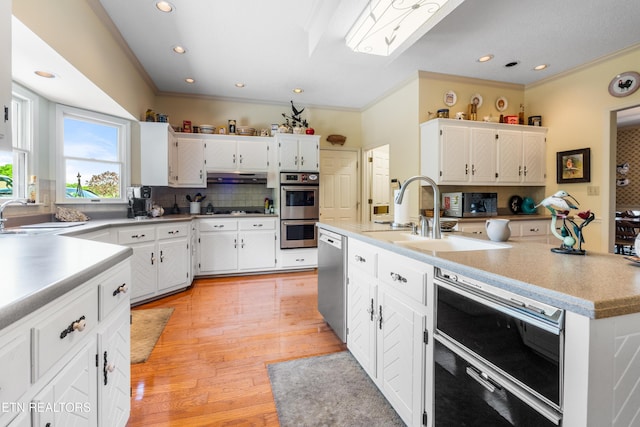 kitchen with backsplash, stainless steel appliances, white cabinetry, and crown molding