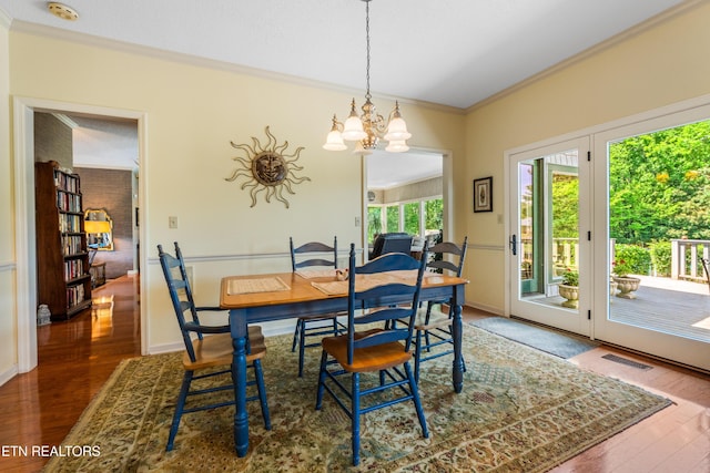 dining space with baseboards, an inviting chandelier, visible vents, crown molding, and wood finished floors