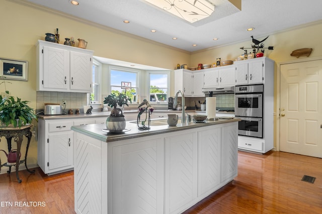 kitchen featuring white cabinetry, decorative backsplash, and stainless steel double oven