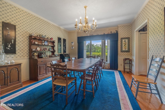 dining room featuring crown molding, wood finished floors, and wallpapered walls