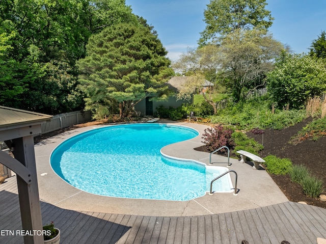outdoor pool featuring a patio, a fenced backyard, and a wooden deck