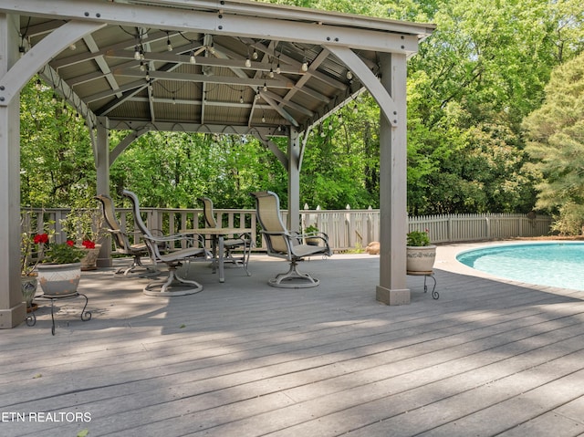 exterior space featuring fence, a gazebo, a wooden deck, and a fenced in pool