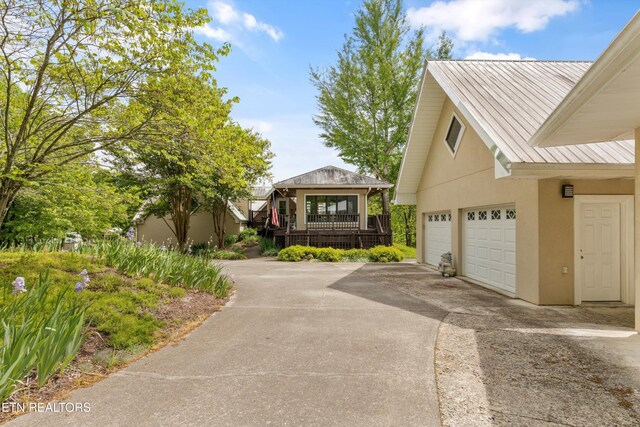 view of side of home featuring stucco siding, driveway, and metal roof
