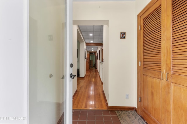 hallway featuring recessed lighting, baseboards, and tile patterned floors