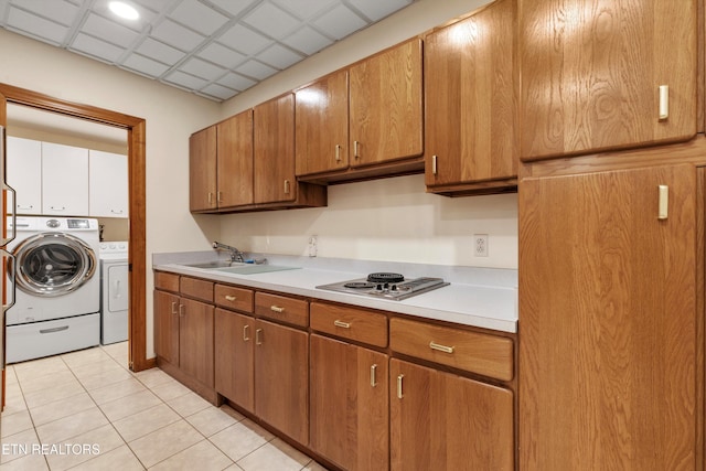 kitchen featuring a sink, stainless steel stovetop, washing machine and dryer, light countertops, and brown cabinets