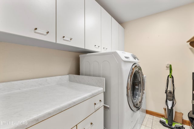 clothes washing area with cabinet space, light tile patterned flooring, independent washer and dryer, and baseboards