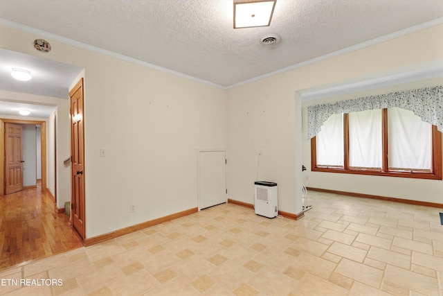 unfurnished room with baseboards, a textured ceiling, and ornamental molding