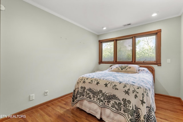 bedroom featuring baseboards, wood finished floors, ornamental molding, and recessed lighting