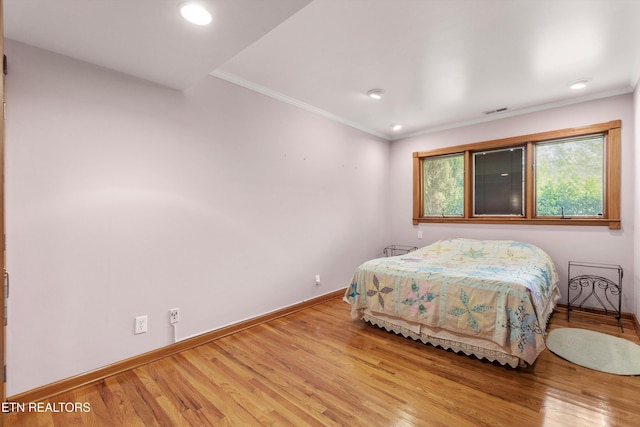 bedroom with wood finished floors, baseboards, ornamental molding, and recessed lighting
