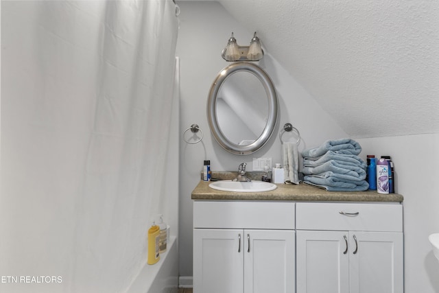 full bathroom featuring vaulted ceiling, vanity, a textured ceiling, and toilet