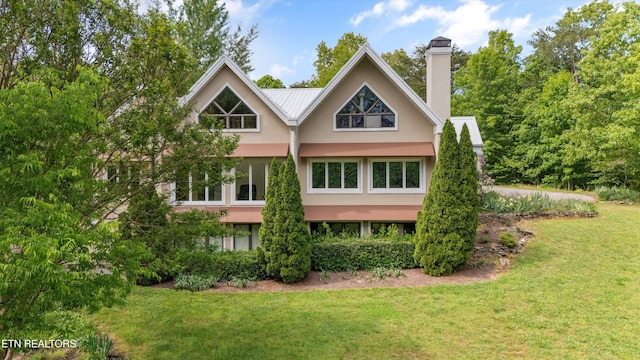 rear view of property featuring stucco siding, a yard, and a chimney