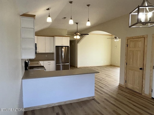 kitchen featuring freestanding refrigerator, lofted ceiling, wood finished floors, and ceiling fan with notable chandelier