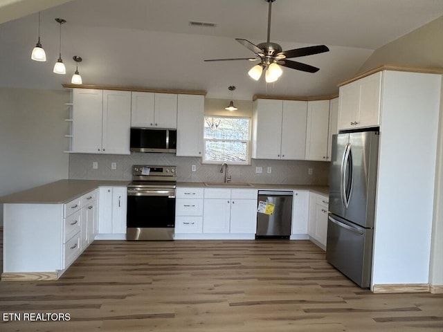 kitchen with lofted ceiling, ceiling fan, a sink, light wood-style floors, and appliances with stainless steel finishes