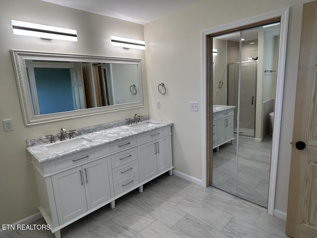full bath with a sink, a stall shower, double vanity, and baseboards