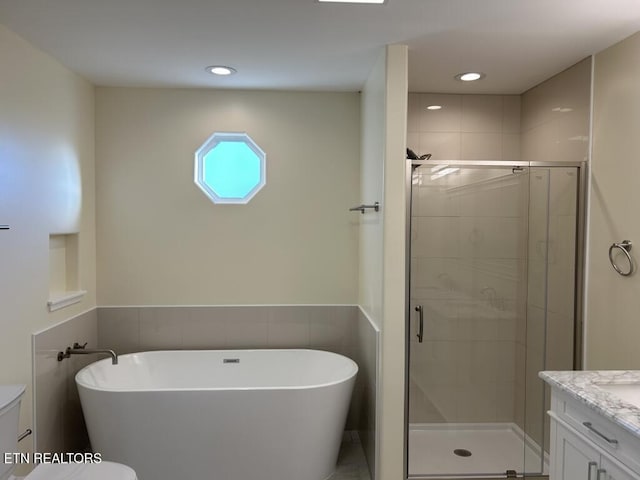 full bath featuring a stall shower, recessed lighting, toilet, vanity, and a freestanding tub