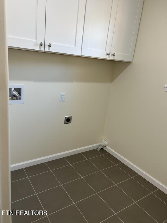laundry room featuring dark tile patterned floors, electric dryer hookup, cabinet space, hookup for a washing machine, and baseboards