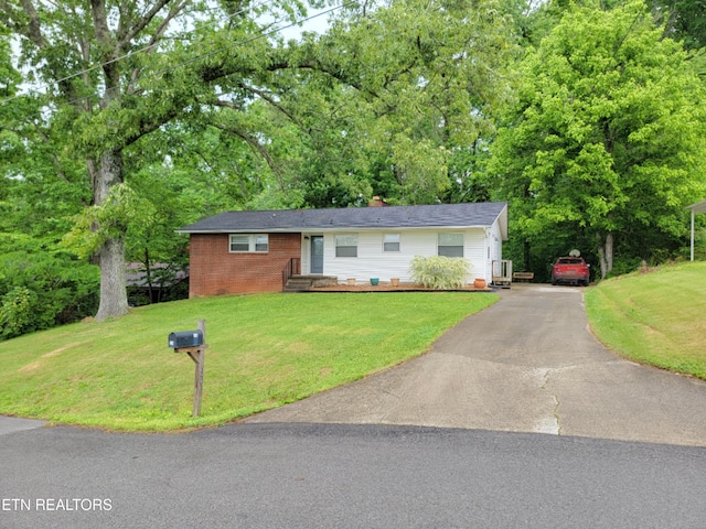 single story home with a front lawn, brick siding, a chimney, and aphalt driveway