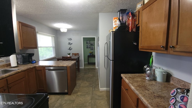 kitchen featuring brown cabinetry, stainless steel appliances, a textured ceiling, and a peninsula