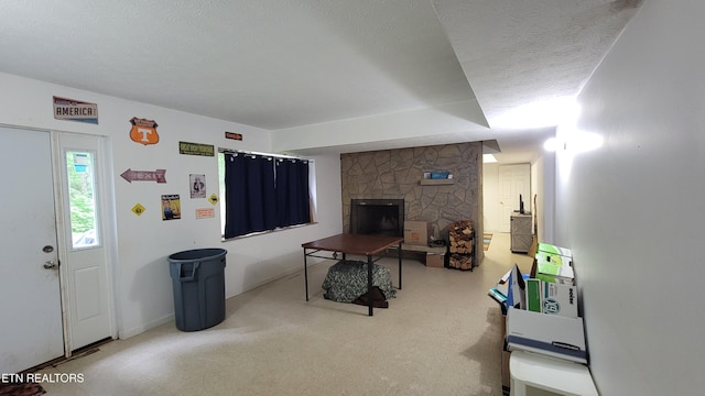living area featuring a textured ceiling, baseboards, and a stone fireplace