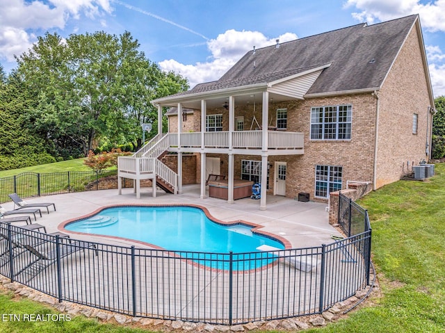 rear view of property featuring a hot tub, brick siding, a patio area, and stairs