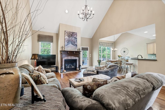 living area featuring a chandelier, high vaulted ceiling, wood finished floors, and a premium fireplace