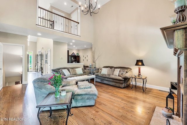 living room featuring a towering ceiling, wood finished floors, baseboards, and a chandelier