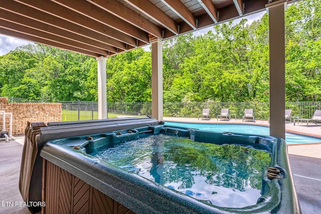view of pool featuring a hot tub, a fenced backyard, and a patio area