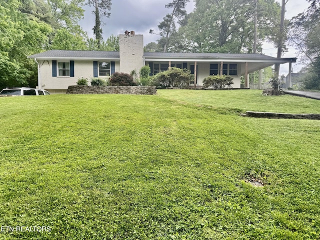 back of house featuring a chimney, a yard, and an attached carport