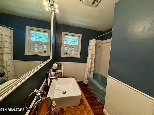 full bath with visible vents, wood finished floors, wainscoting, and a sink