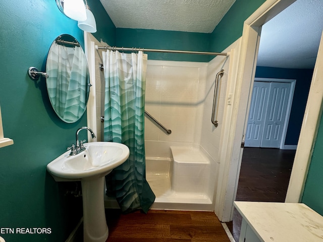full bathroom with a textured ceiling, a shower with shower curtain, and wood finished floors