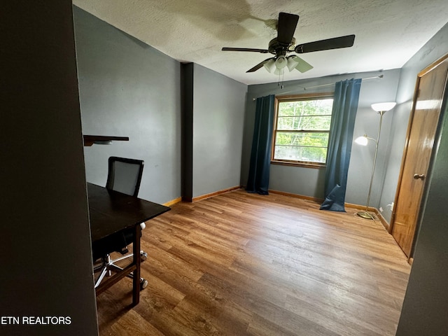 unfurnished office featuring baseboards, a ceiling fan, a textured ceiling, and wood finished floors