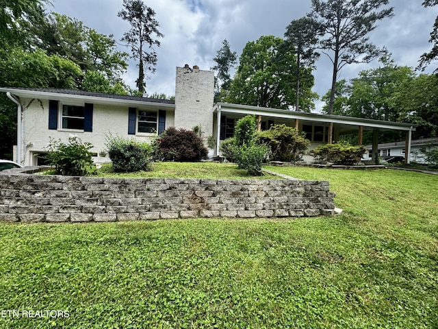 rear view of house with a yard, brick siding, and a chimney