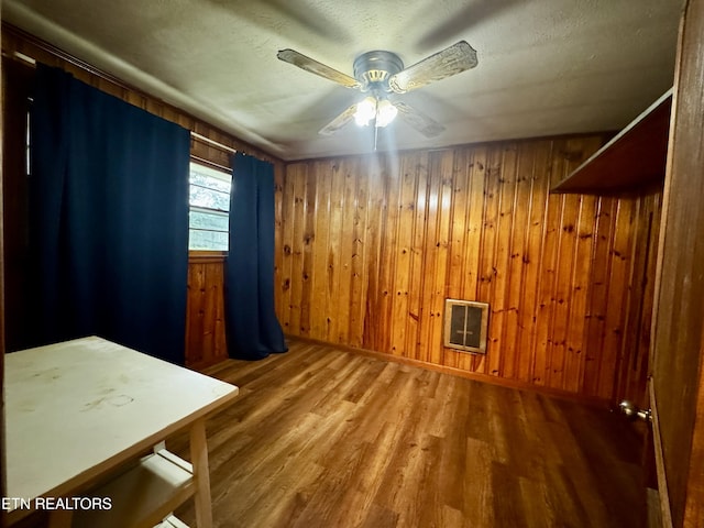 interior space featuring wood walls, wood finished floors, and a ceiling fan