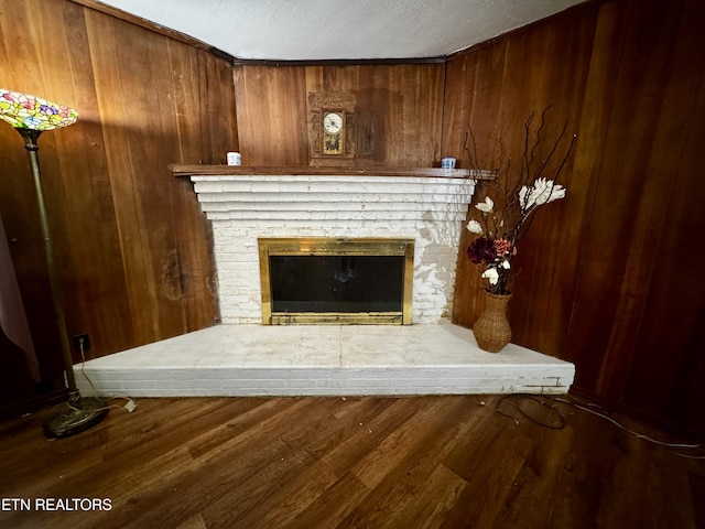 interior details featuring wooden walls, a fireplace, a textured ceiling, and wood finished floors