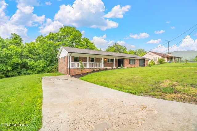 7220 Beelertown Rd, Powell, TN 37849 - ranch-style house featuring covered porch, brick siding, a front lawn, and driveway