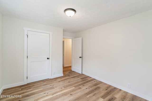 7220 Beelertown Rd, Powell, TN 37849 - unfurnished bedroom featuring light wood-type flooring, baseboards, and a textured ceiling