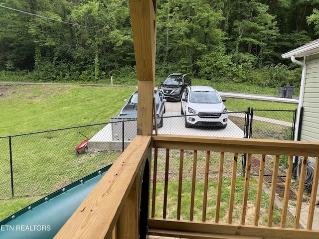 wooden deck with a yard, a wooded view, fence, and a gate