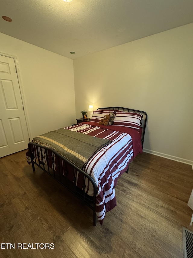 bedroom with visible vents, wood finished floors, and baseboards