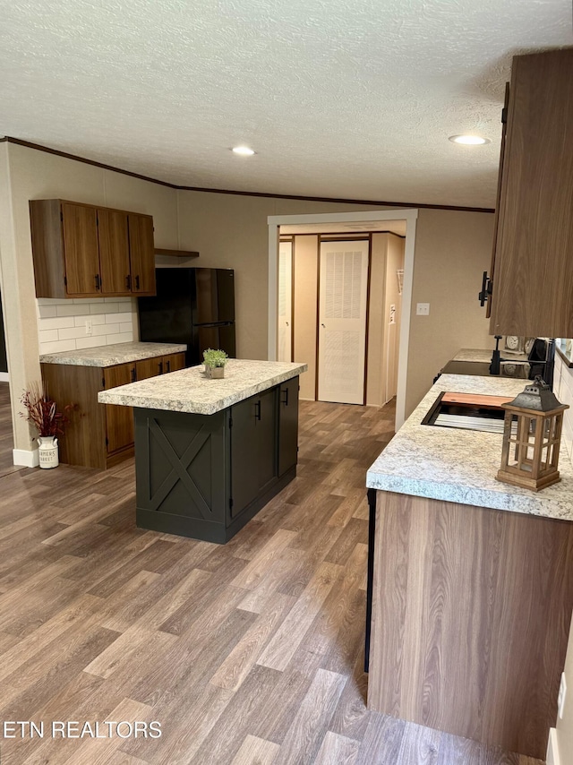 kitchen with freestanding refrigerator, light countertops, a textured ceiling, and wood finished floors