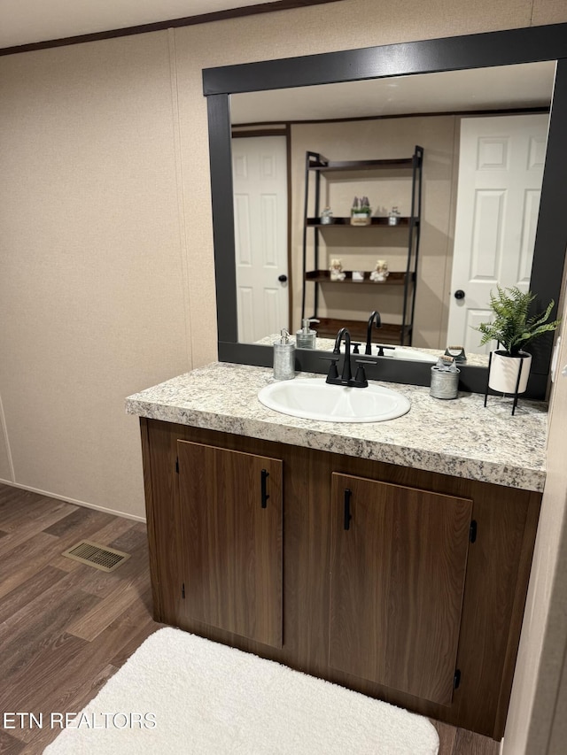 bathroom with ornamental molding, vanity, visible vents, and wood finished floors