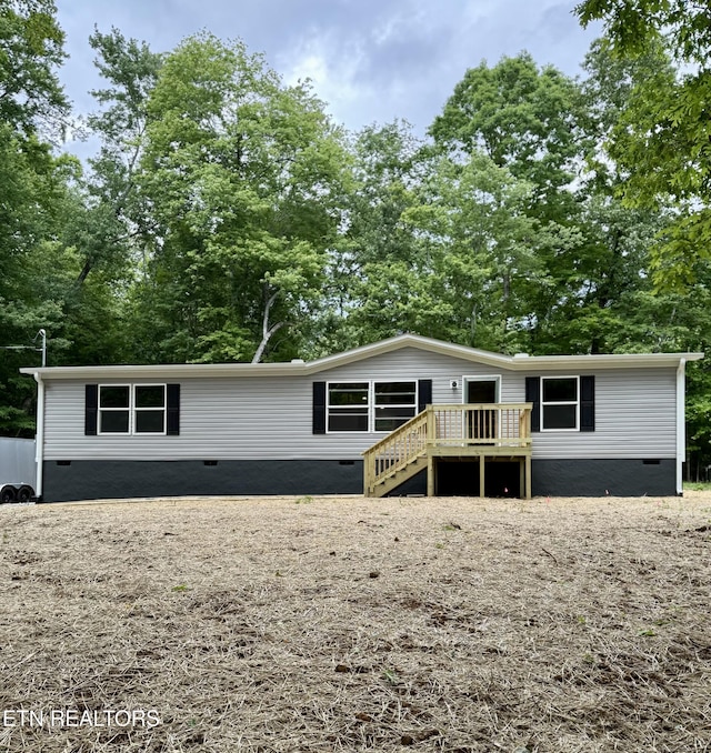 view of front of home with crawl space, a wooden deck, and stairs