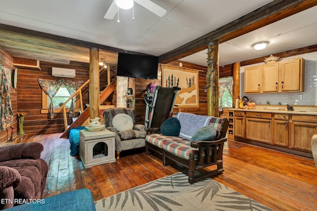 living area featuring wooden walls, hardwood / wood-style floors, stairway, ceiling fan, and a wall mounted AC