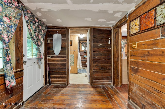 foyer entrance with hardwood / wood-style flooring and wooden walls